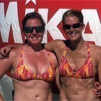 two beach volleyball players standing and posing for a picture outside